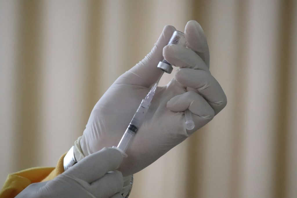 close up image of clinician extracting vaccine with syringe.