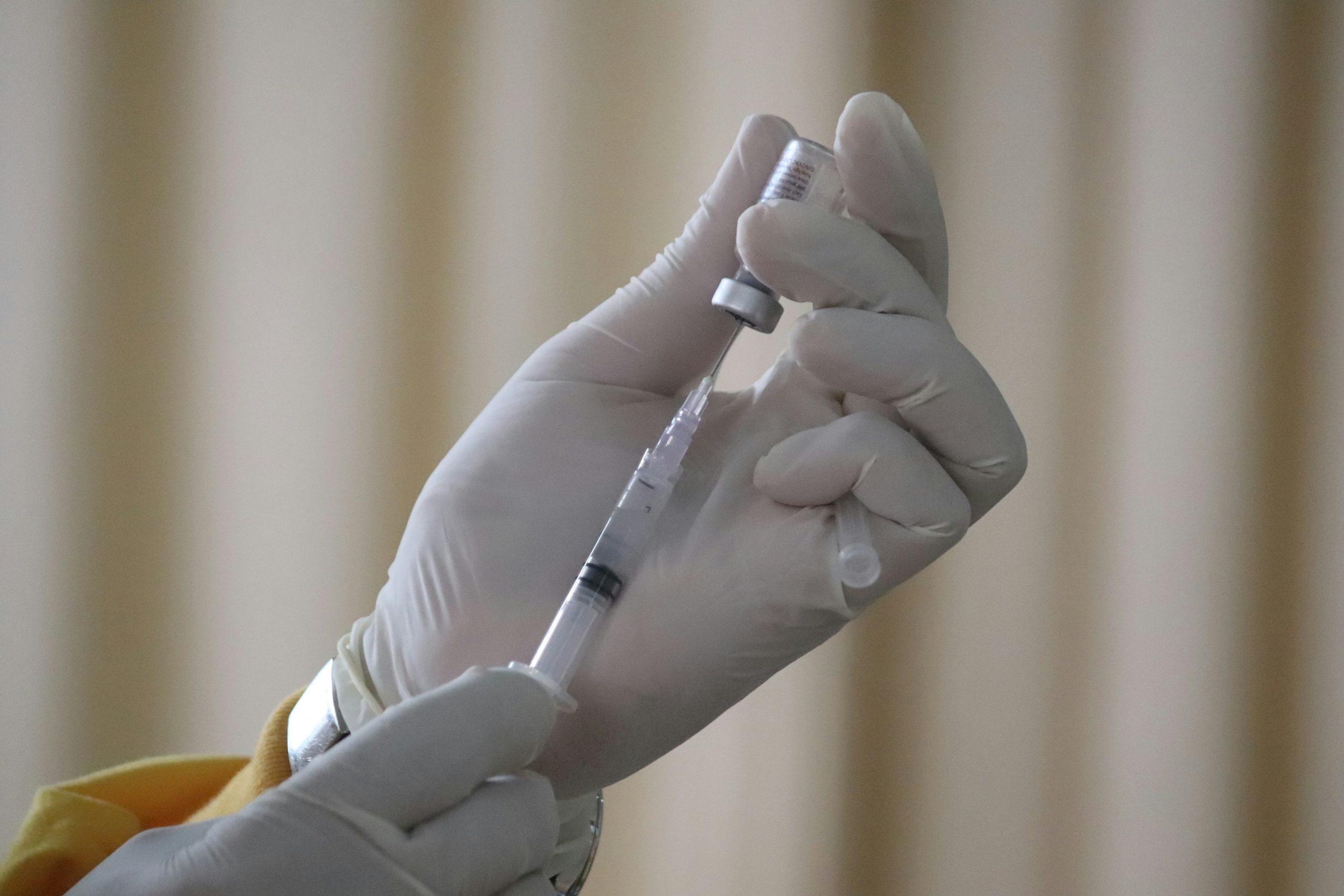 close up image of clinician extracting vaccine with syringe.